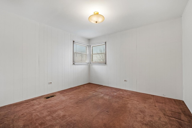 unfurnished room with wood walls and carpet floors