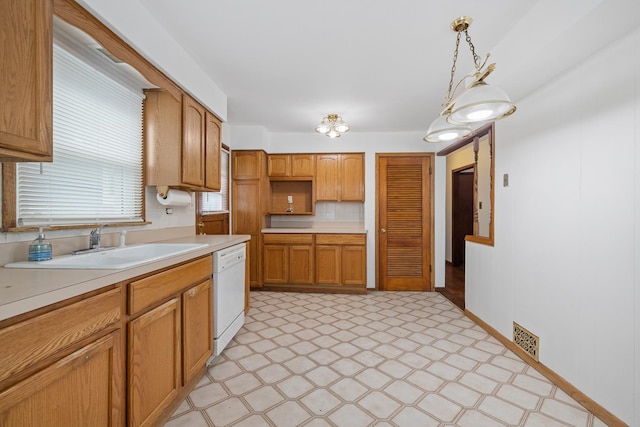 kitchen featuring white dishwasher, backsplash, pendant lighting, and sink