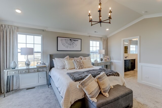 bedroom featuring lofted ceiling, light carpet, an inviting chandelier, crown molding, and connected bathroom