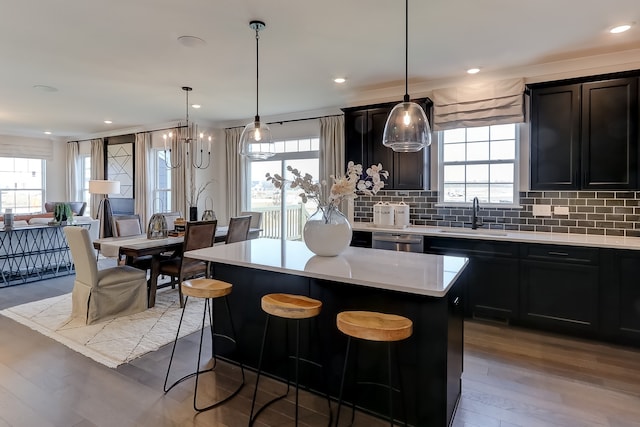 kitchen featuring sink, hanging light fixtures, stainless steel dishwasher, decorative backsplash, and a kitchen island