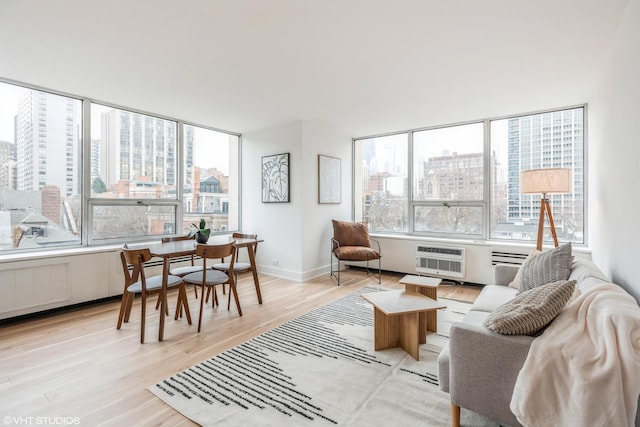 living room featuring light wood-type flooring, a wall unit AC, and a wealth of natural light