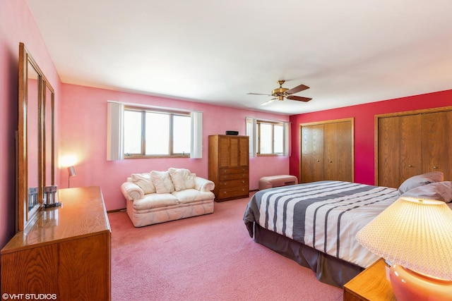 bedroom featuring ceiling fan, multiple closets, and carpet flooring