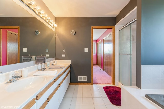 bathroom featuring a shower with shower door, visible vents, a sink, and tile patterned floors