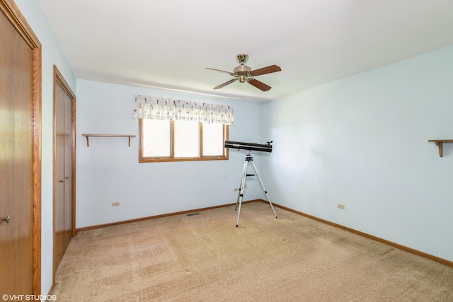 spare room with baseboards, visible vents, a ceiling fan, and light colored carpet