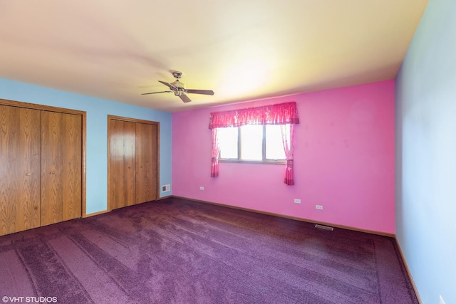 unfurnished bedroom featuring ceiling fan, carpet floors, and multiple closets