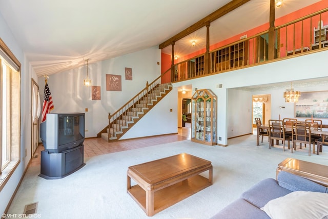 carpeted living room with beamed ceiling, high vaulted ceiling, and an inviting chandelier