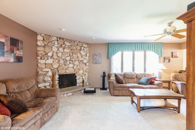 living room featuring a fireplace, ceiling fan, and light carpet