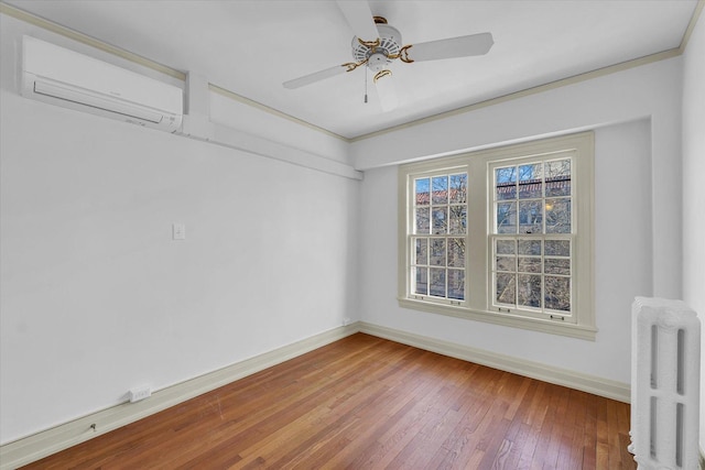 empty room with radiator, a wall mounted air conditioner, wood-type flooring, ornamental molding, and ceiling fan