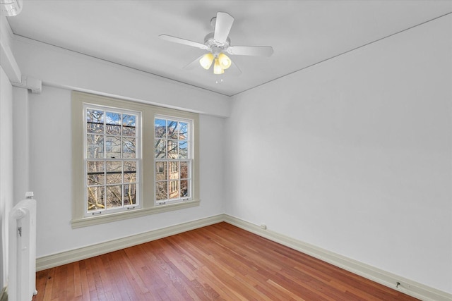 empty room with hardwood / wood-style floors and ceiling fan