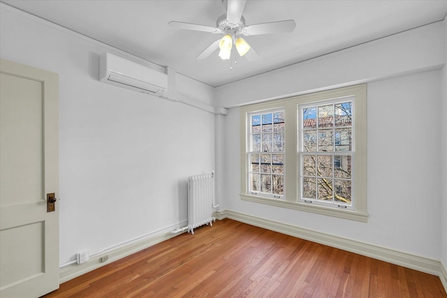 empty room featuring ceiling fan, radiator heating unit, hardwood / wood-style floors, and a wall mounted air conditioner