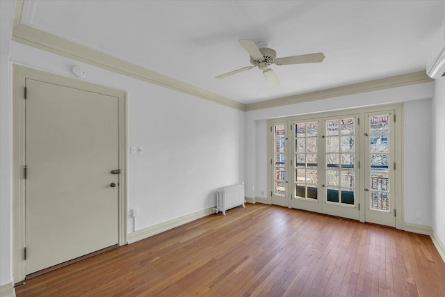 spare room featuring crown molding, ceiling fan, wood-type flooring, and radiator