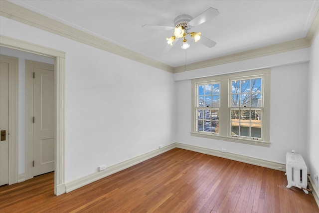 spare room with ceiling fan, ornamental molding, radiator heating unit, and wood-type flooring