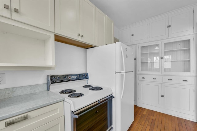 kitchen with white cabinetry, wood-type flooring, and white appliances