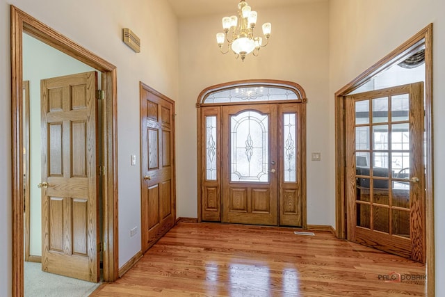 entryway featuring a towering ceiling, an inviting chandelier, and light hardwood / wood-style floors