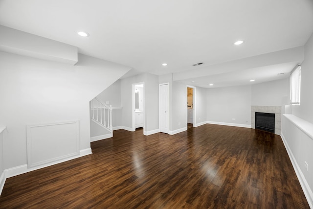 unfurnished living room with dark hardwood / wood-style flooring and a tiled fireplace