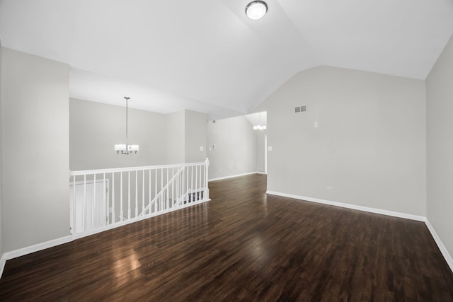 spare room with dark hardwood / wood-style flooring, an inviting chandelier, and lofted ceiling