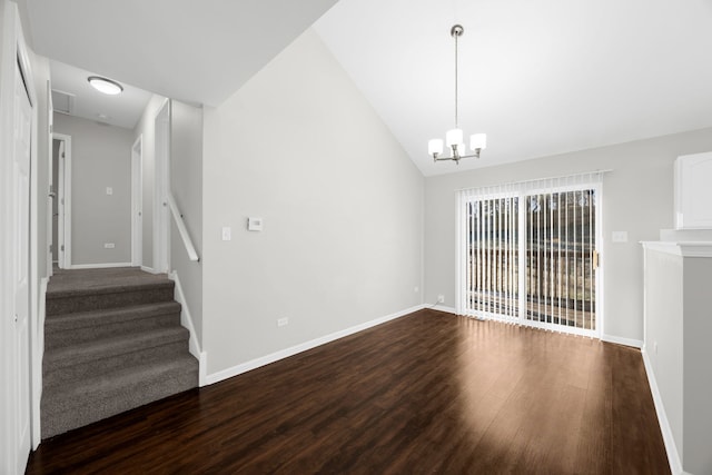 empty room featuring dark hardwood / wood-style floors, vaulted ceiling, and an inviting chandelier