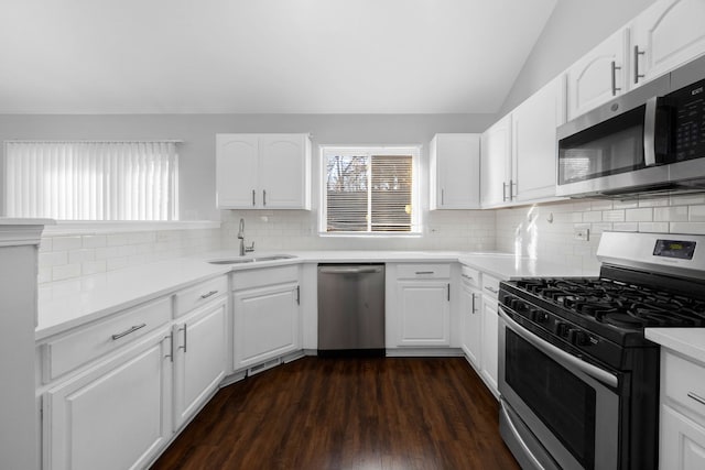 kitchen featuring dark wood-type flooring, sink, vaulted ceiling, white cabinetry, and stainless steel appliances