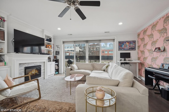 living room with ceiling fan, hardwood / wood-style flooring, a high end fireplace, and ornamental molding