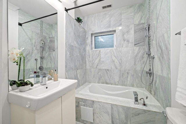 full bathroom featuring toilet, vanity, and tiled shower / bath