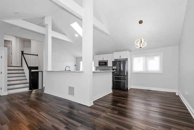 kitchen with stainless steel refrigerator with ice dispenser, kitchen peninsula, decorative light fixtures, beam ceiling, and white cabinetry