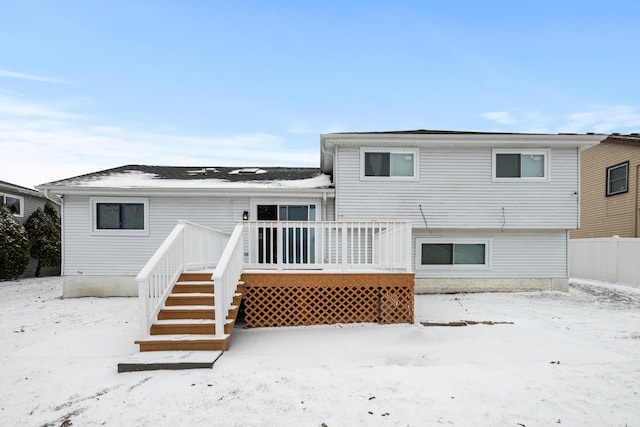 snow covered back of property with a deck