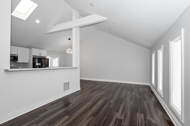 unfurnished living room featuring beamed ceiling, dark hardwood / wood-style flooring, a skylight, and high vaulted ceiling