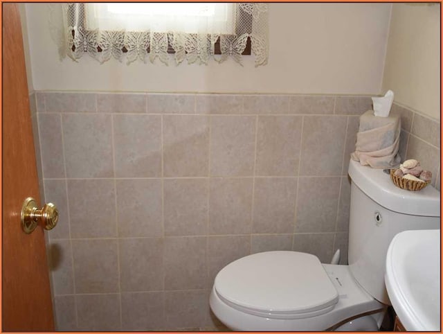 bathroom featuring tile walls, sink, and toilet