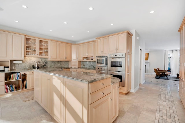 kitchen with light stone counters, a center island, stainless steel appliances, and tasteful backsplash