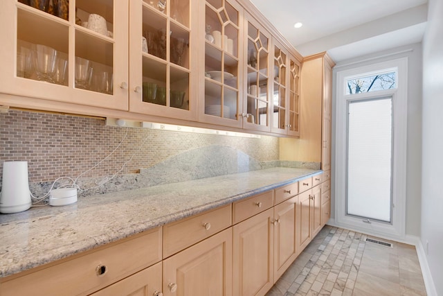 kitchen featuring decorative backsplash, light brown cabinets, and light stone countertops