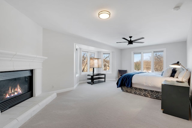 bedroom featuring light carpet, ceiling fan, and a tile fireplace