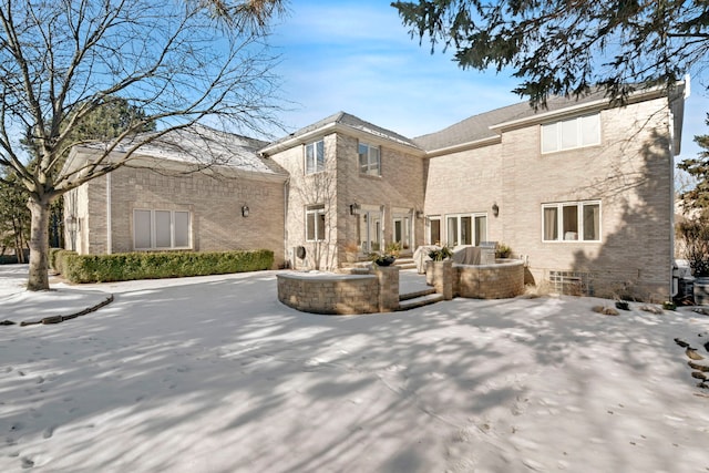 snow covered back of property featuring a patio area