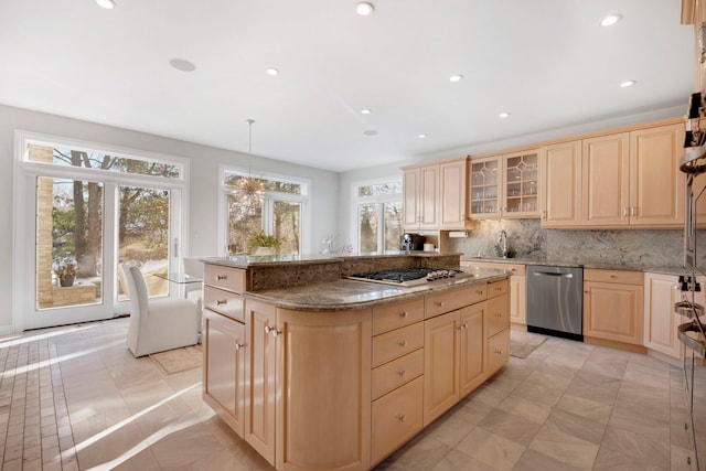 kitchen with light brown cabinets, stainless steel appliances, dark stone counters, and a kitchen island