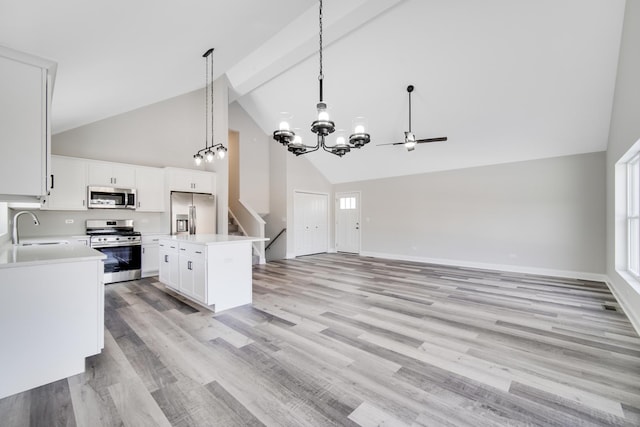 kitchen with a center island, white cabinets, sink, decorative light fixtures, and stainless steel appliances