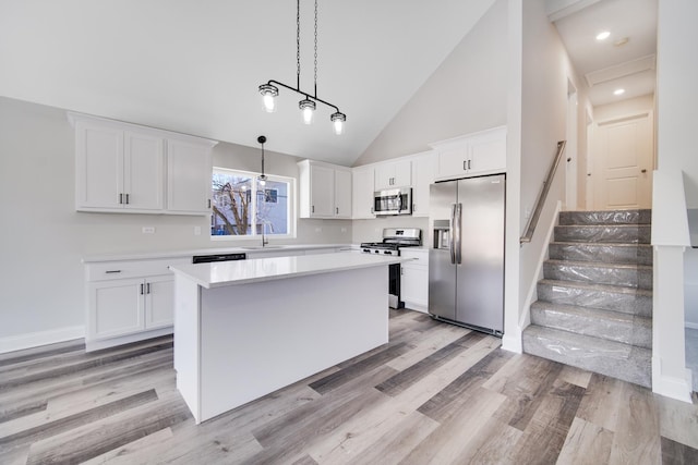 kitchen with stainless steel appliances, sink, high vaulted ceiling, white cabinets, and a kitchen island