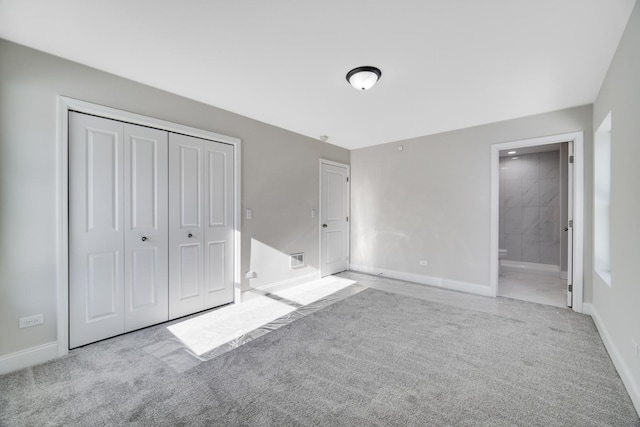 unfurnished bedroom featuring light carpet, connected bathroom, and a closet