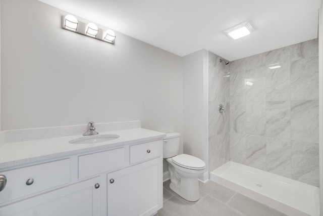 bathroom with a tile shower, vanity, toilet, and tile patterned floors