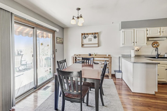 dining room featuring wood-type flooring, sink, and a chandelier