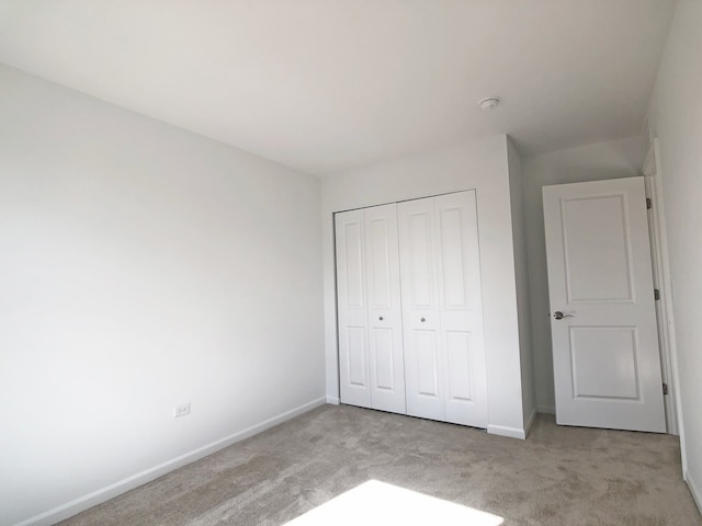 unfurnished bedroom with light colored carpet and a closet