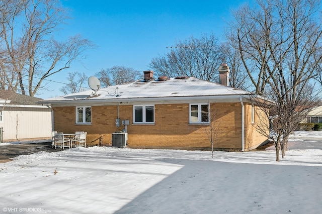 snow covered back of property featuring central air condition unit