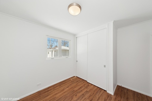 unfurnished bedroom with hardwood / wood-style flooring, a closet, and crown molding