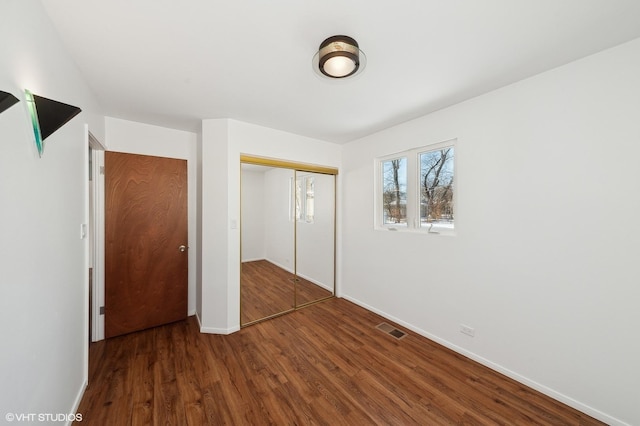 unfurnished bedroom with dark wood-type flooring and a closet