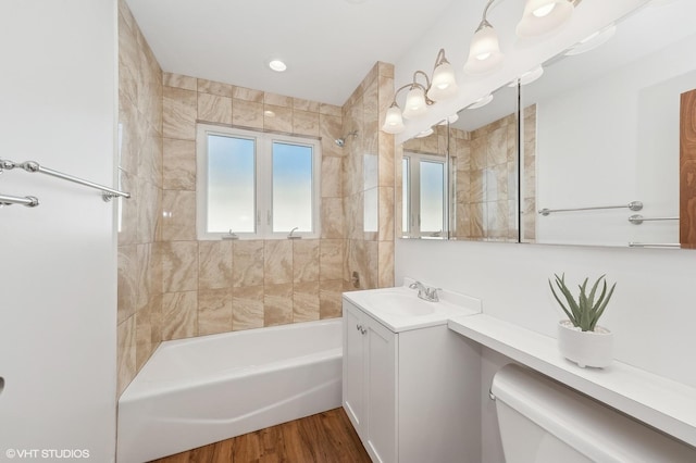 full bathroom featuring toilet, tiled shower / bath combo, wood-type flooring, and vanity