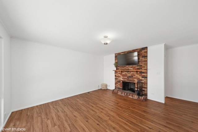 unfurnished living room featuring wood-type flooring, ornamental molding, and a fireplace