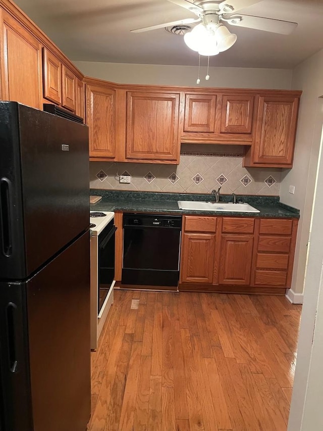 kitchen featuring sink, light hardwood / wood-style flooring, ceiling fan, backsplash, and black appliances