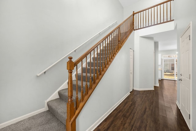 stairs featuring a towering ceiling and wood-type flooring