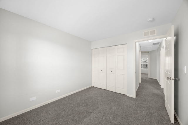 unfurnished bedroom featuring dark carpet and a closet