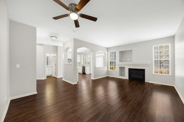 unfurnished living room featuring a tile fireplace, ceiling fan, and dark hardwood / wood-style floors