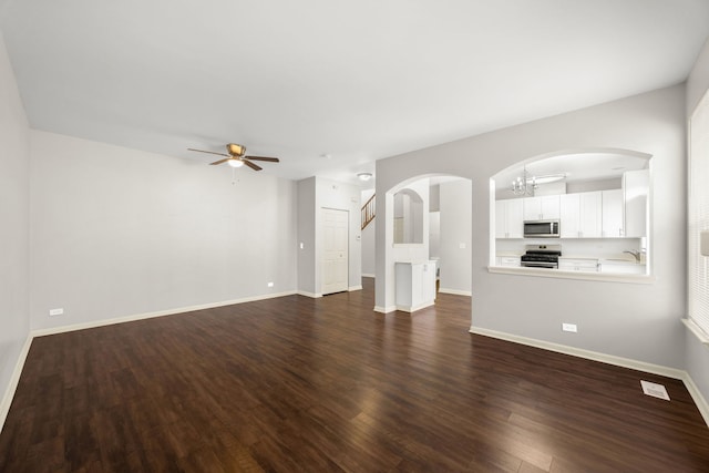 unfurnished living room with sink, dark wood-type flooring, and ceiling fan with notable chandelier