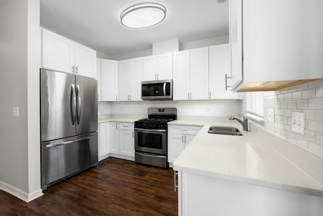 kitchen with appliances with stainless steel finishes, dark hardwood / wood-style flooring, white cabinetry, and sink